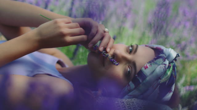 Woman with lavender flowers relaxing on field