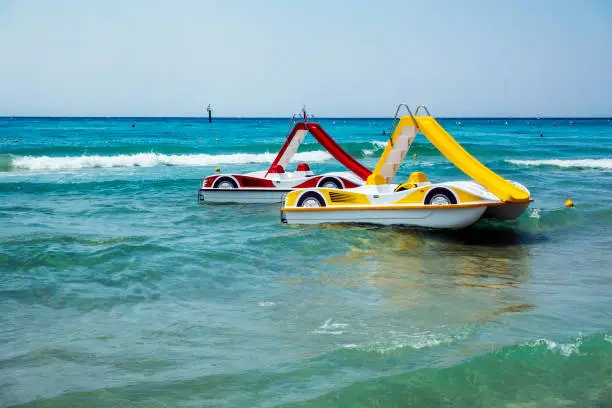 Two pedal-boats with water slides on the beach in Greece.