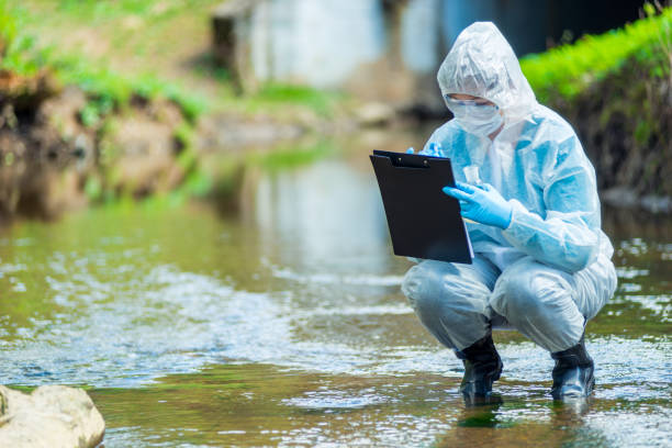 die arbeit eines wissenschaftlers ökologe, ein porträt eines mitarbeiters, der eine studie des wassers in einem bach durchführt - umweltkatastrophe stock-fotos und bilder