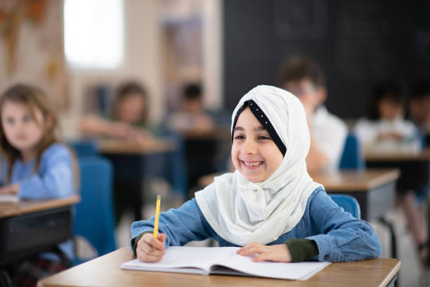 istock Muslim Girl Writing in her Notebook in Class 1158716676