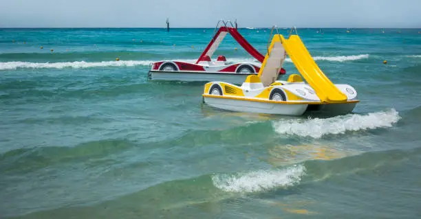 Two pedal-boats with water slides on the beach in Greece.