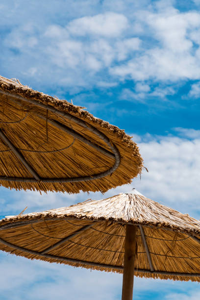 istock Two straw parasols on beach in Skala Kallonis, Mytilene, (Lesbos Island), Greece 1158717678
