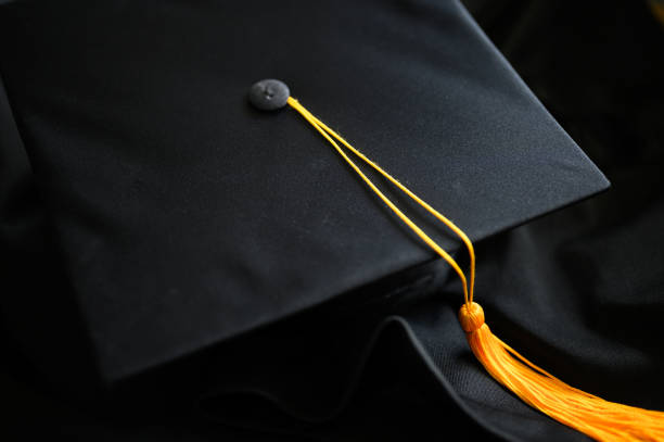 "nclose-up black graduation hat and yellow tassel placed on the floor - toga imagens e fotografias de stock