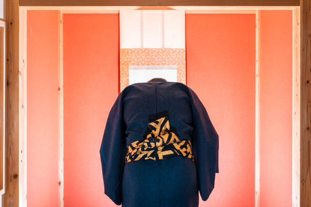 pièce japonaise traditionnelle avec la fenêtre et l'alcôve coulissantes avec le rouleau suspendu et la couleur rouge avec l'homme dans l'inclinaison de kimono - obi sash photos et images de collection