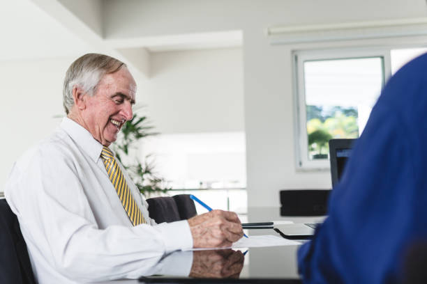 istock Senior business man smiling while signing documents at corporate office 1158722519