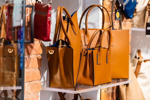 Many leather purse bags in Siena Italy with orange brown color hanging on display in shopping street market in city