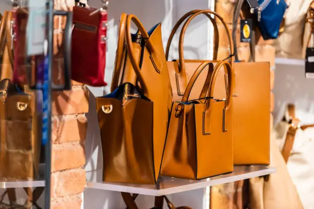 Photo of Many leather purse bags in Siena Italy with orange brown color hanging on display in shopping street market in city