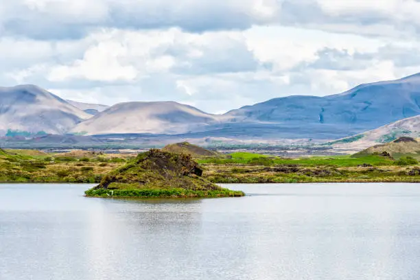 Landscape view of Iceland mountains in Skutustadagigar with lake Myvatn during cloudy day and calm tranquil water and mound in summer