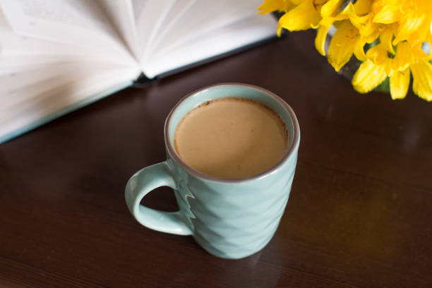 istock cup of coffee, yellow flowers and a book on a table 1158728700