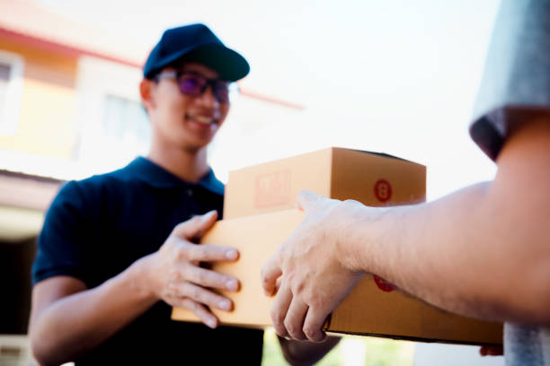 istock Asian cargo carrier holds a cardboard box with the package inside and the recipient is signing the package. 1158730588