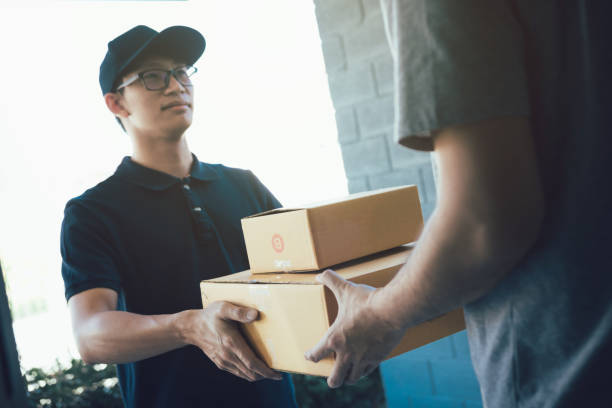 istock Asian cargo carrier holds a cardboard box with the package inside and the recipient is signing the package. 1158730657