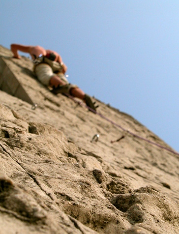 A sport's fanatic is climbing an artificial wall, he's almost at the top.