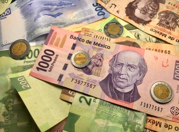 istock Many mixed Mexican peso bills spread over a wooden desk 1158740236