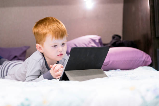 istock Little Redhead Boy Watching a Television Show on Digital Tablet in Camper Trailer 1158740542