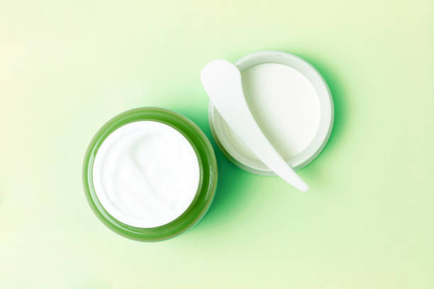 istock Green jar with white cream and plastic spatula on background, top view 1158746417