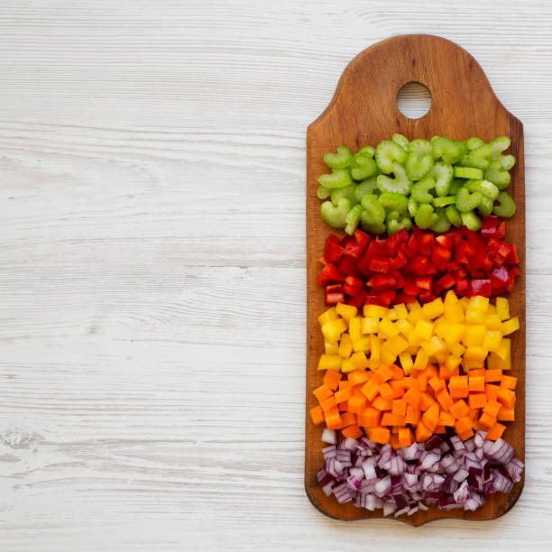 istock Top view, chopped fresh vegetables (carrot, celery, red onion, colored peppers) arranged on cutting board on a white wooden surface. Flat lay, from above, top view. Copy space. 1158748966