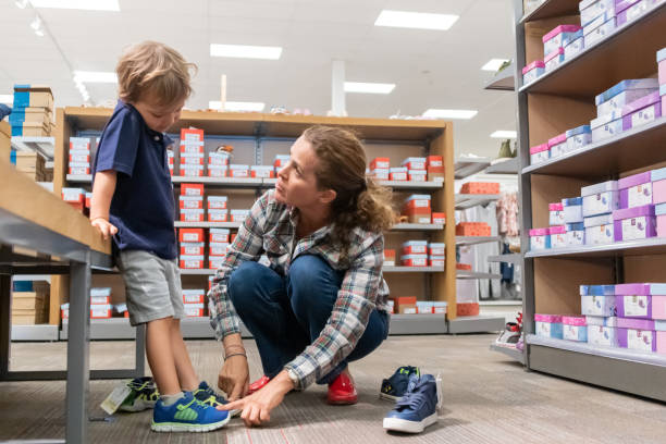 彼女の息子のための靴のための成熟した女性の買い物 - shoe store shoe shopping retail ストックフォトと画像