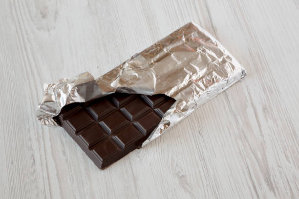 istock Dark chocolate in a wrapper over white wooden surface, low angle view. Close-up. 1158749187