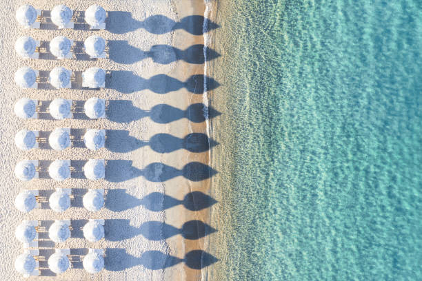 View from above, stunning aerial view of an amazing empty white beach with white beach umbrellas and turquoise clear water during sunset. Mediterranean sea, Sardinia, Italy. View from above, stunning aerial view of an amazing empty white beach with white beach umbrellas and turquoise clear water during sunset. Mediterranean sea, Sardinia, Italy. beach umbrella aerial stock pictures, royalty-free photos & images