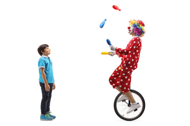 boy watching a clown juggling and riding a unicycle - entertainment clown child circus imagens e fotografias de stock