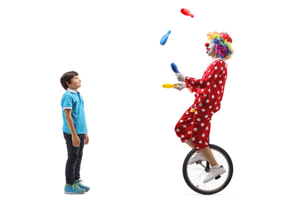 мальчик смотрит клоун жонглирование и езда на одноколесном велосипеде - unicycle стоковые фото и изображения
