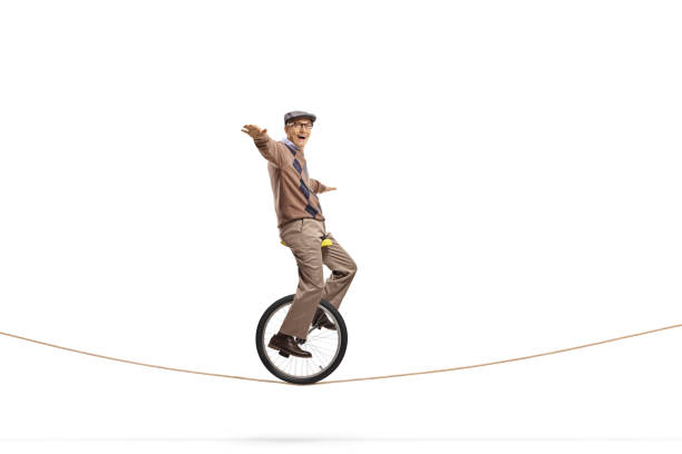 istock Senior man riding a unicycle on a rope 1158757408