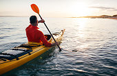 Senior kayaker at sunset sea