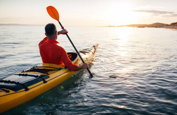 Senior kayaker at sunset sea stock photo