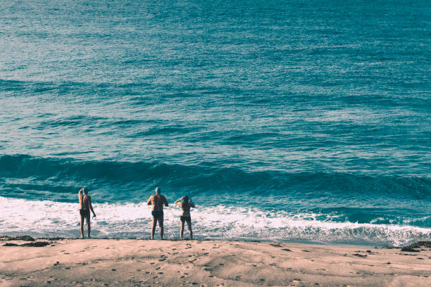Newcastle, Australia - June 16 2019 two men and a lady preparing to take a morning swim in the pacific ocean