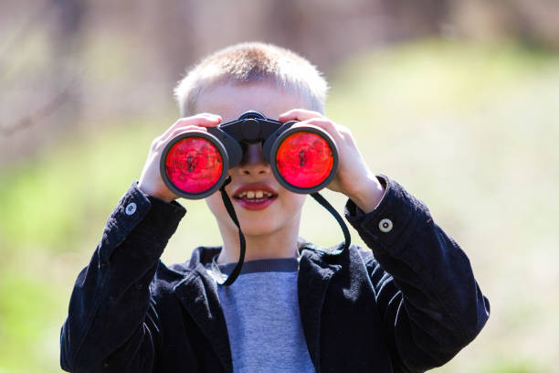 istock Portrait of little cute handsome cute blond boy watching intently something through binoculars in distance on blurred background. Children innocence, dreams, fantasies and imaginations concept. 1158760121