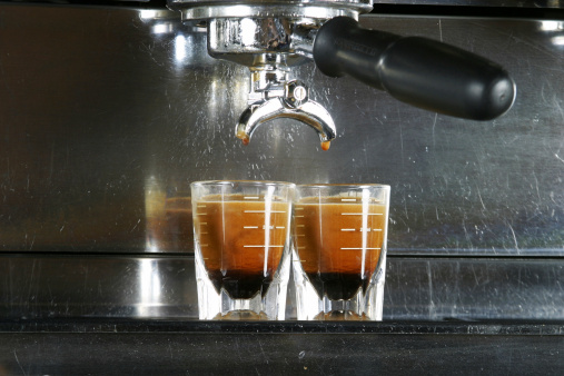 Two shots of espresso being drawn from a professional espresso machine.