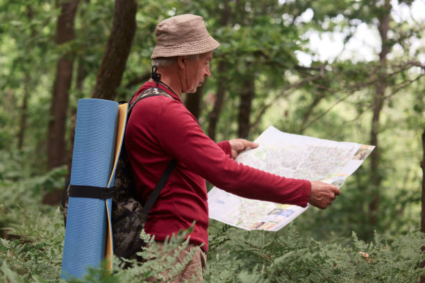 istock Image of old man traveling, having active rest, spending his vocation backpacking, standing with map, tries to find right way. Traveling, active recreation, adventure, spending time in open fresh air. 1158760944