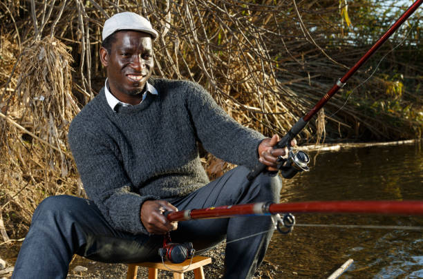 istock Positive fisherman sitting near river 1158763486