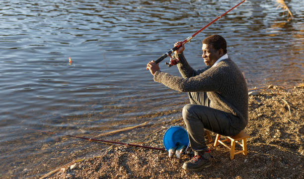 istock Positive fisherman sitting near river 1158763503