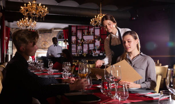 istock Young female waiter taking order from visitors in luxurious restaurant 1158769366