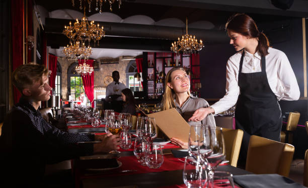istock Young female waiter taking order from visitors in luxurious restaurant 1158769371