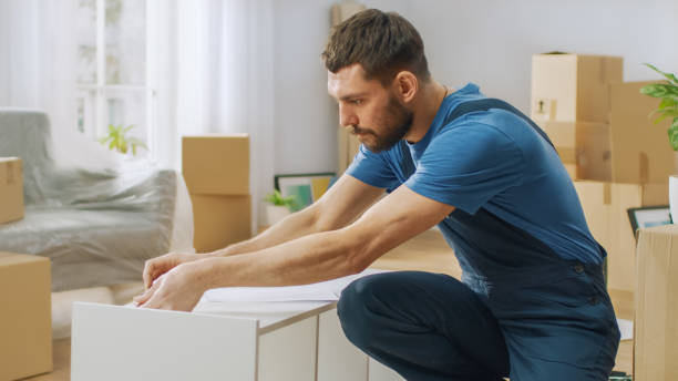 istock Furniture Assembly Worker Assembles Bookshelf. Professional Handyman Doing Assembly Job Well, Helping People who Move into New House. 1158770069
