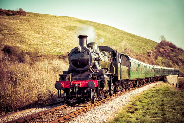 Steam Train Gently Moving Through the English Countryside Steam locomotive pulling out of a station- gorgeous English countryside background locomotive photos stock pictures, royalty-free photos & images