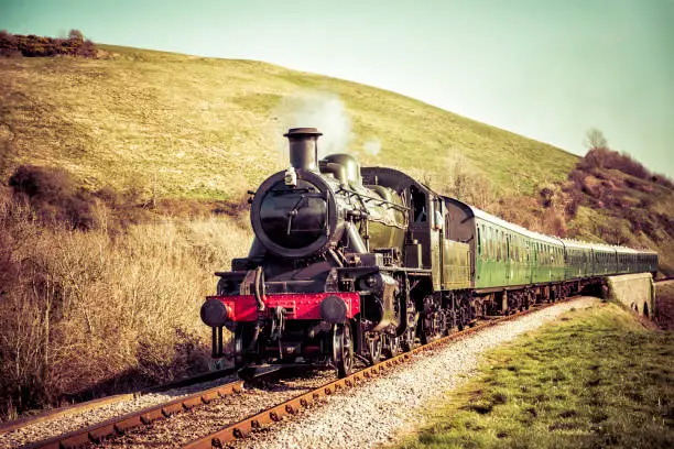 Steam locomotive pulling out of a station- gorgeous English countryside background