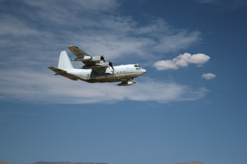 US Marine Corps plane with blue sky and clouds in the back ground. 400MPH, 132ft wing span, 97ft long, 3,000 mile range.  