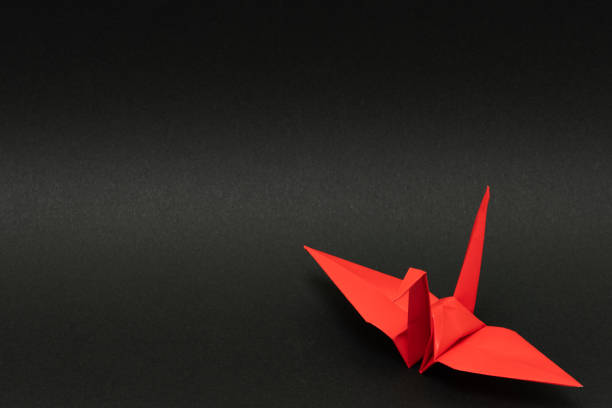 istock red origami paper crane on black background 1158778746