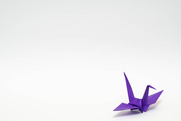 istock purple origami paper crane on white background 1158778761