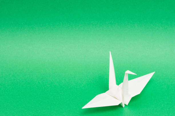 istock white origami paper crane on green background 1158778858