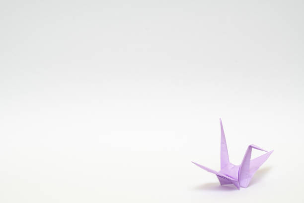 istock light purple origami paper crane on white background 1158778873