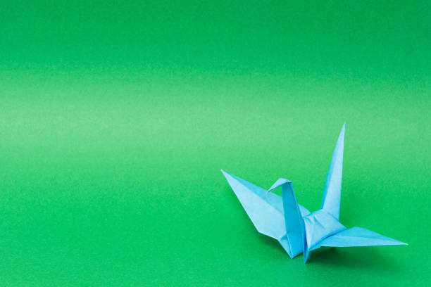 istock light blue origami paper crane on green background 1158778919