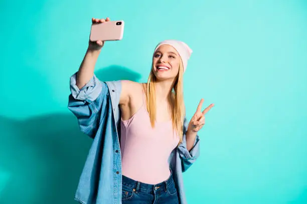 Portrait of her she nice-looking attractive lovely cheerful cheery girl wearing streetstyle clothing taking, selfie showing v-sign isolated on bright vivid shine blue green turquoise background