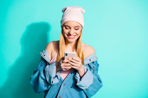 Portrait of her she nice attractive lovely charming cute cheerful cheery girl wearing streetstyle clothing using app 5g device gadget isolated over bright vivid shine blue green turquoise background