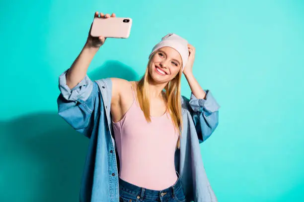 Portrait of her she nice-looking attractive lovely fascinating cheerful, cheery girl wearing streetstyle clothing taking making selfie isolated on bright vivid shine blue green turquoise background