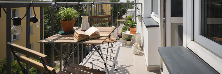Panorama of small balcony with city view and simple wooden table and chairs