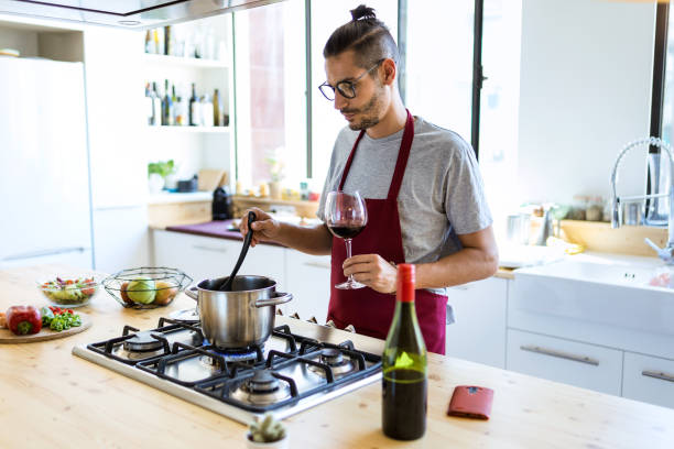 Handsome young man cooking in the kitchen at home.